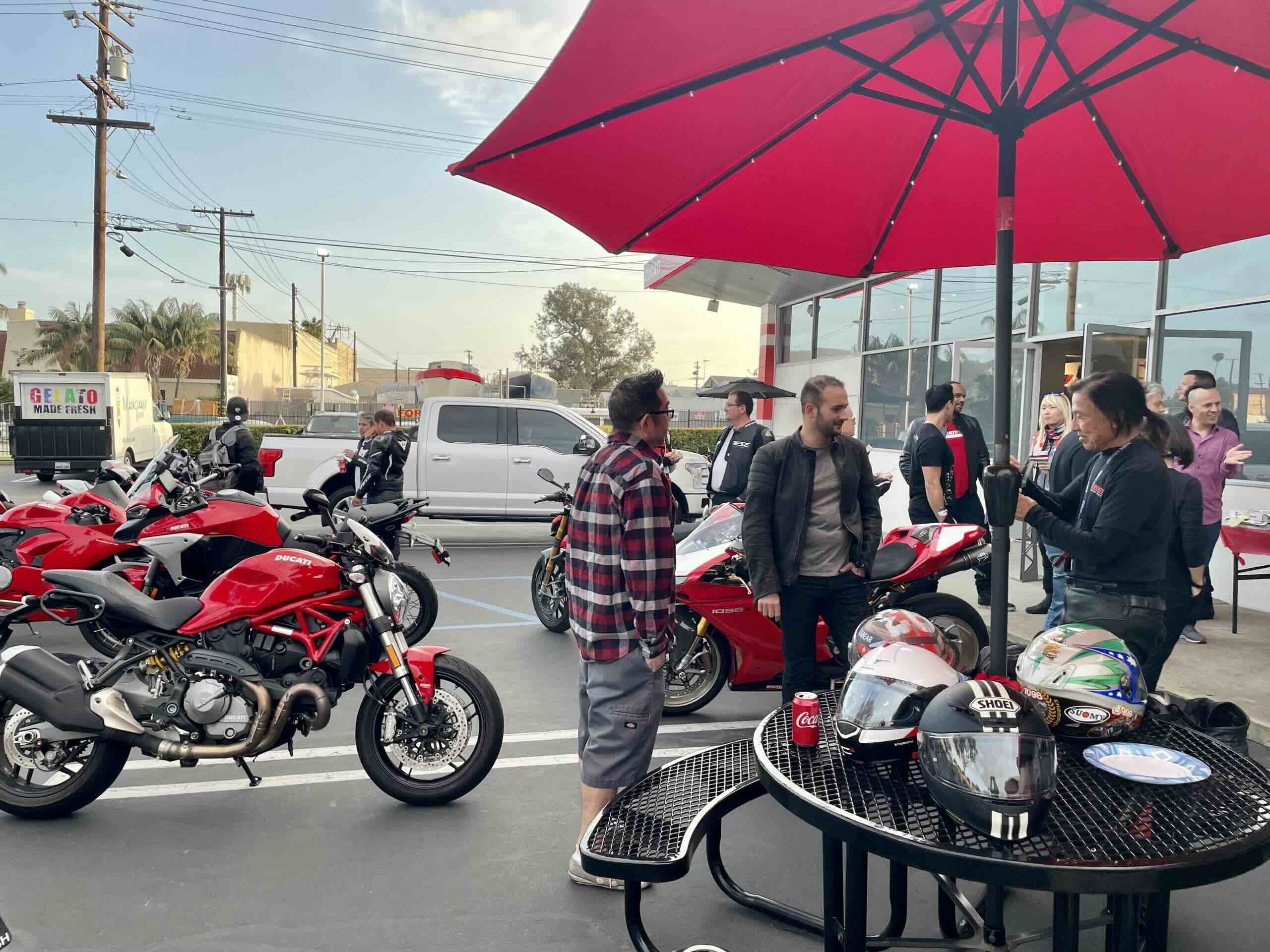 Ducati motorcycles at a bike night event in Orange County with riders socializing under red umbrellas