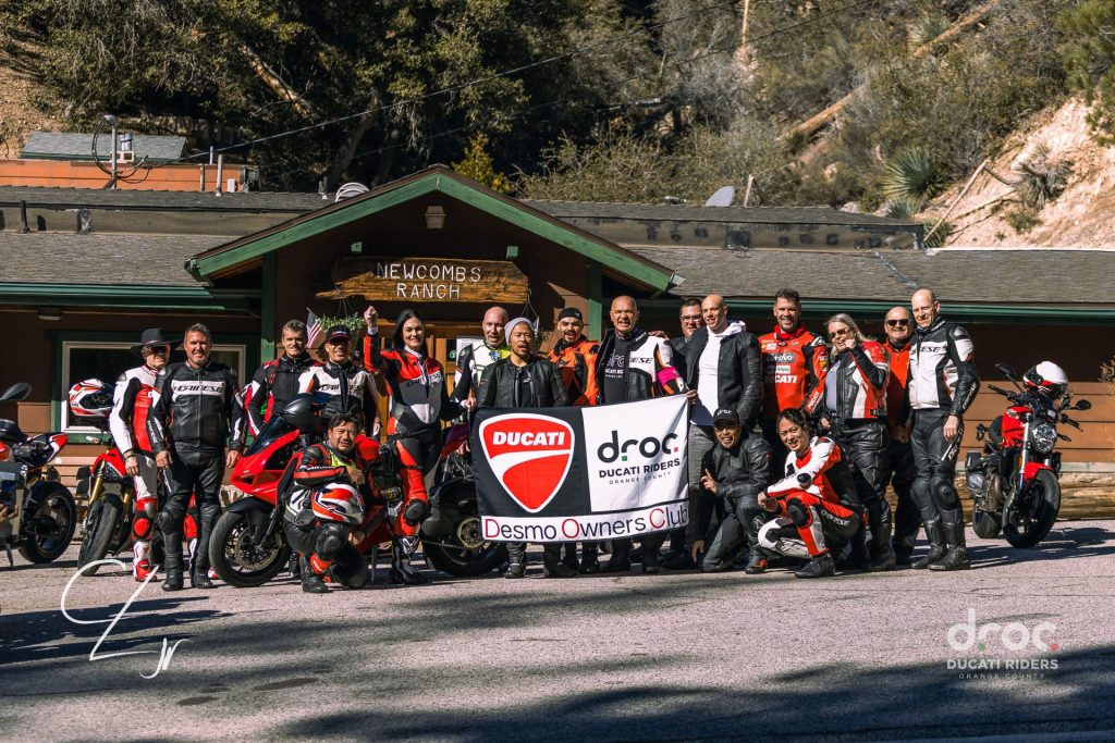 Ride with DROC: the six ways we ride 9 Riders and their Ducatis outside Newcomb's Ranch, holding a Ducati Desmo Owners Club DROC banner