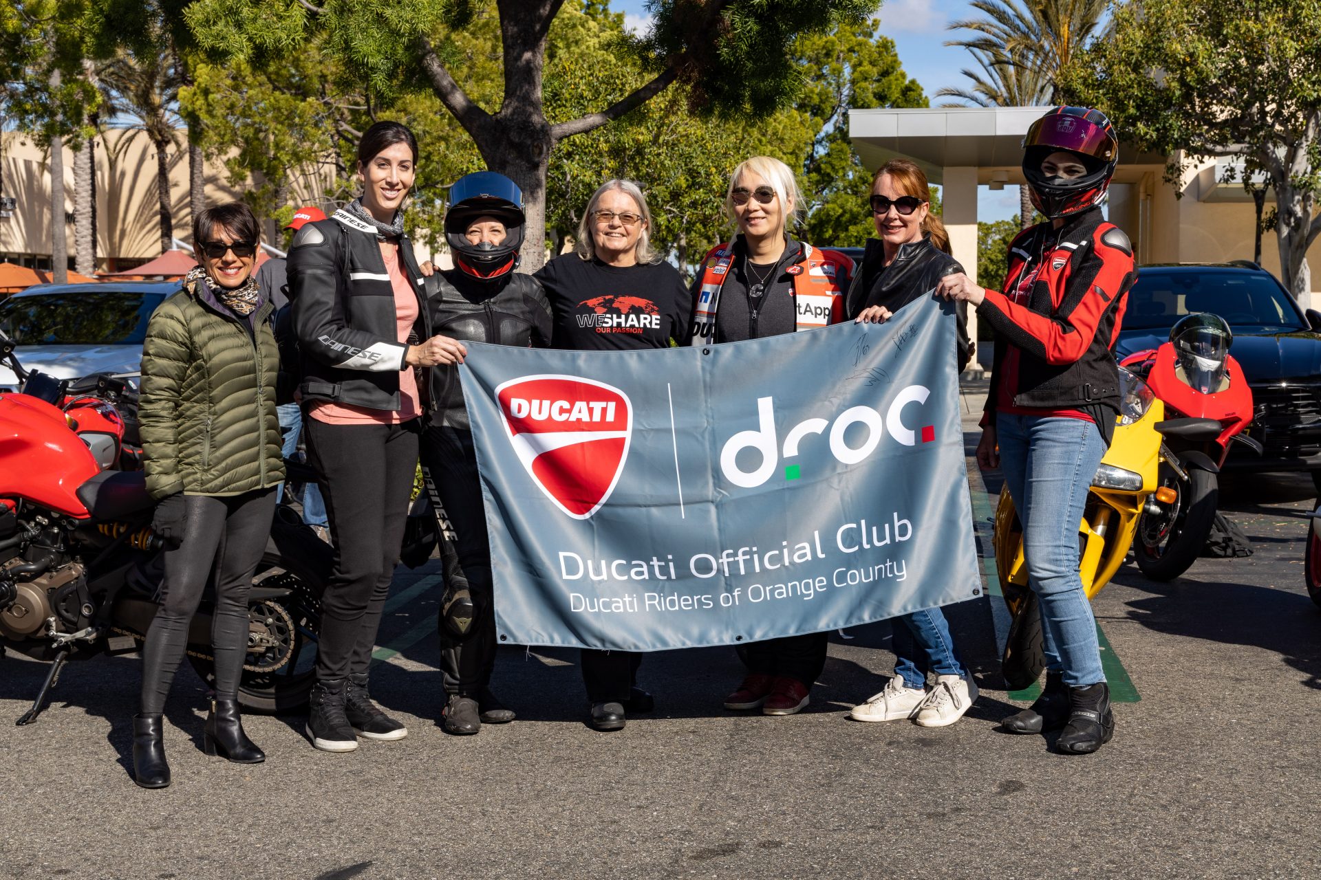 Ducati Riders of Orange County members proudly display their club banner in a sunny outdoor setting