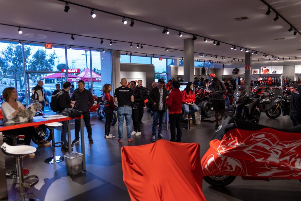Ride with DROC: the six ways we ride 5 People standing among motorcycles in a Ducati showroom, two bikes still under red covers