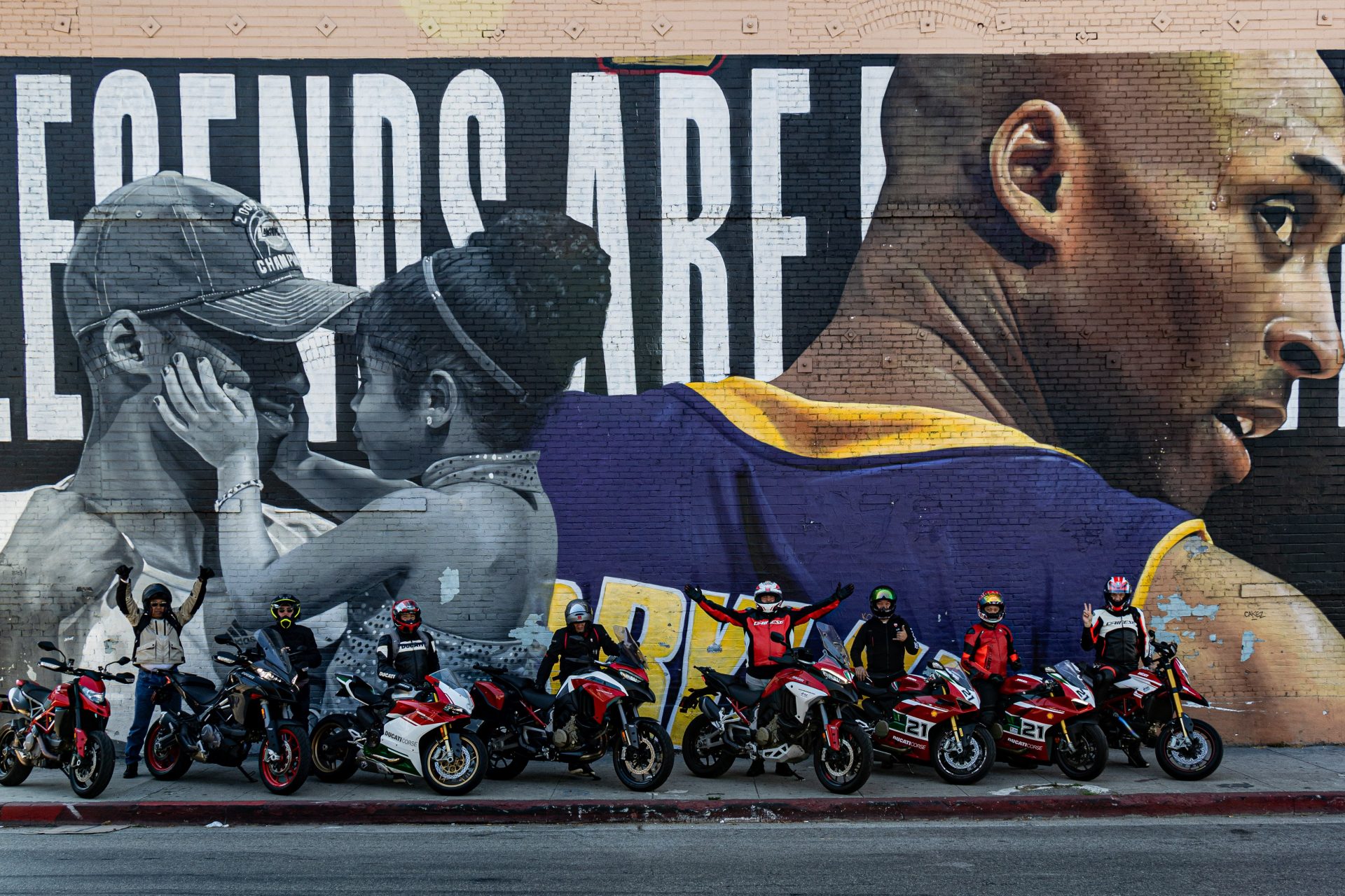 Ducati bikes lined up in front of a mural in Orange County showcasing friendship and community spirit