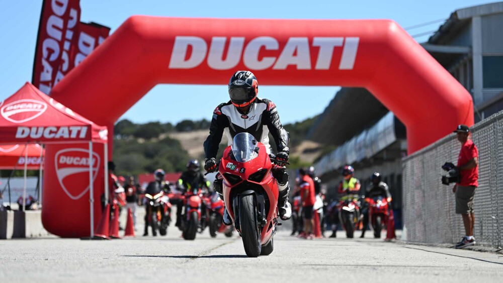 DROC Registration 1 Rider passing under a red Ducati arch at a track day, others waiting nearby