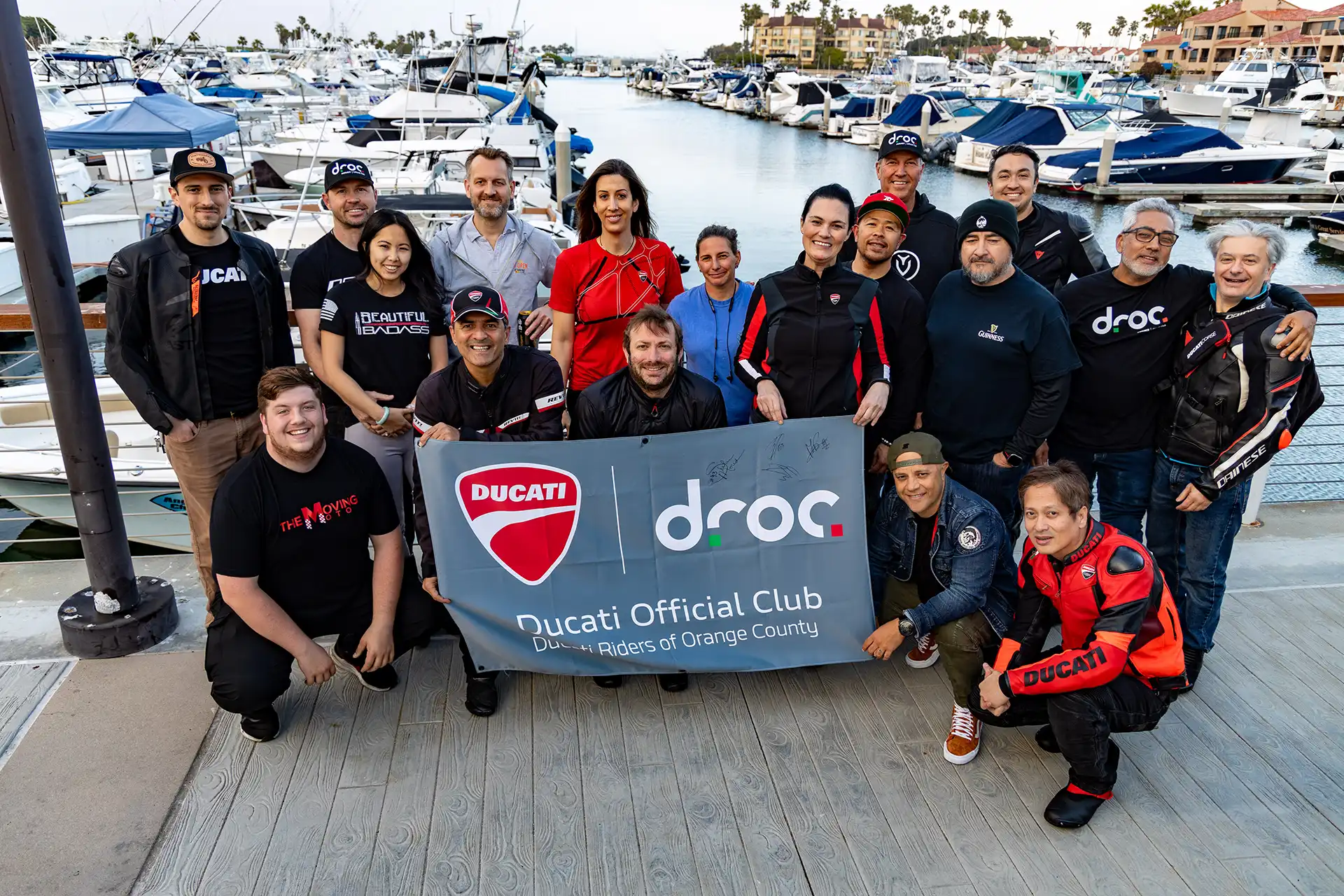 Ducati Riders of Orange County members gather by the marina, showcasing club camaraderie and membership benefits