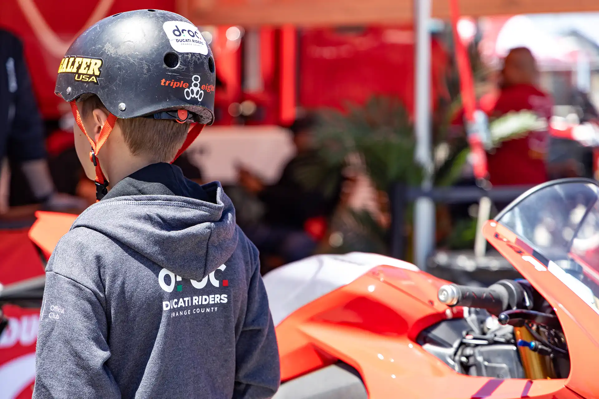 Ducati Riders of Orange County member in a helmet near a Ducati motorcycle at a sunny event