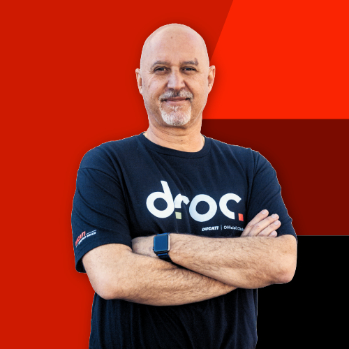 DROC team member in Ducati shirt poses confidently against a bold red background