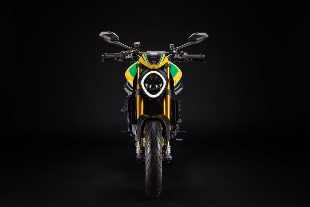 Front view of a yellow, green and blue liveried Ducati Monster motorcycle in a studio
