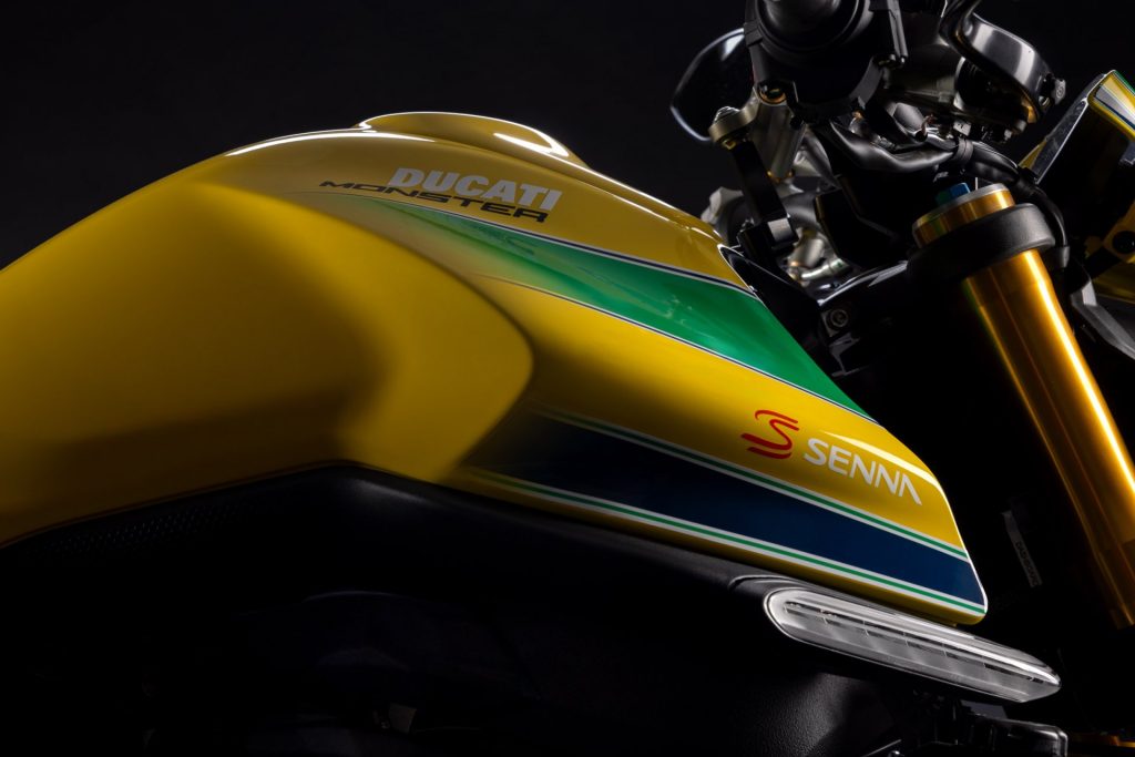 Close-up of a Ducati Monster fuel tank with green and blue stripes and a Senna logo