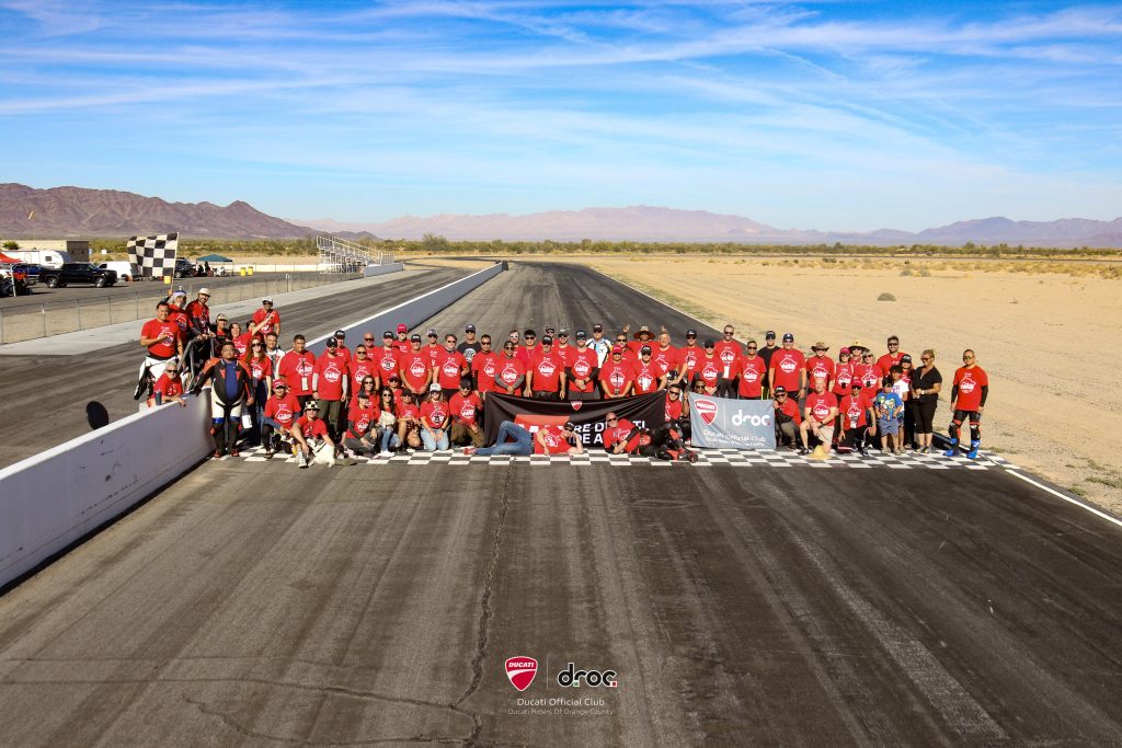 A large group of DROC members and riders poses on the track at Chuckwalla Valley Raceway at the 5th DROC Track Day, November 2025