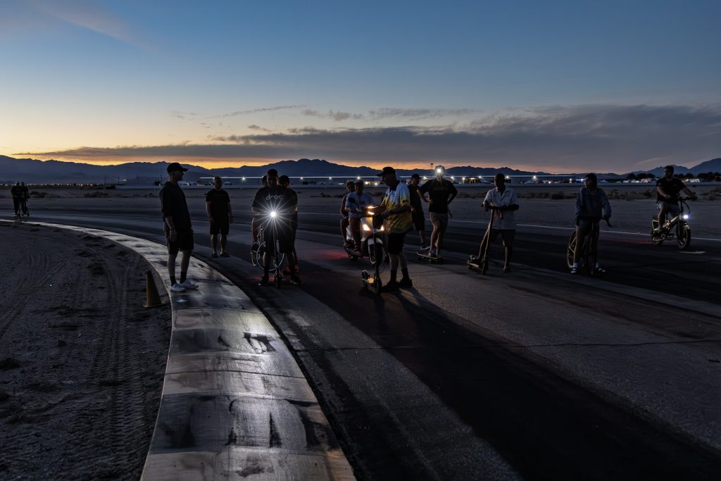 Riders and bikes gather on the track at Chuckwalla Valley Raceway under a dusk sky, November 2025