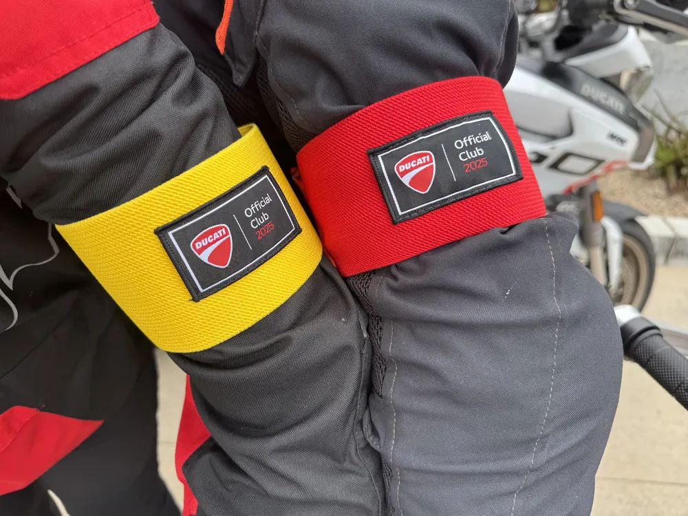 Yellow and red armbands with "DUCATI Official Club 2023" on black patches, worn on motorcycle jackets.