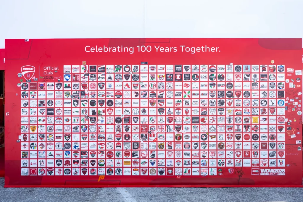 Ride with DROC: the six ways we ride 26 Wall of several hundred Ducati Official Club badges at World Ducati Week 2026, under the words Celebrating 100 Years Together