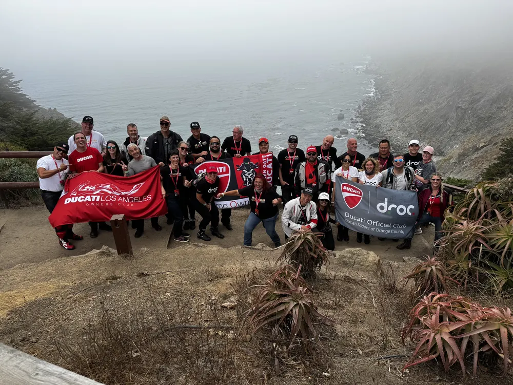 Ride with DROC: the six ways we ride 21 Ducati Los Angeles Owners Club and DROC banners held by a group at a foggy coastal overlook