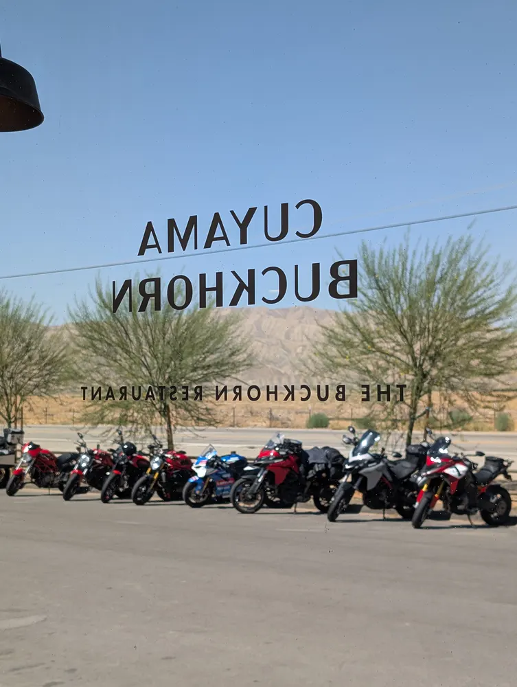 Cuyama Buckhorn restaurant sign reflected in window with several motorcycles parked outside