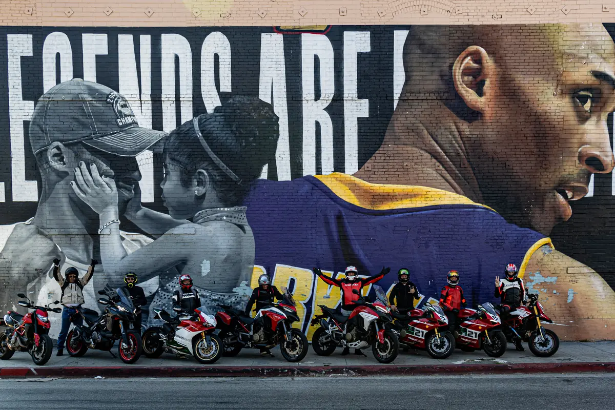 6th Street Viaduct and DTLA rides 7 Eight Ducatis and their riders lined up along the kerb in front of the Kobe and Gianna Bryant mural in Los Angeles
