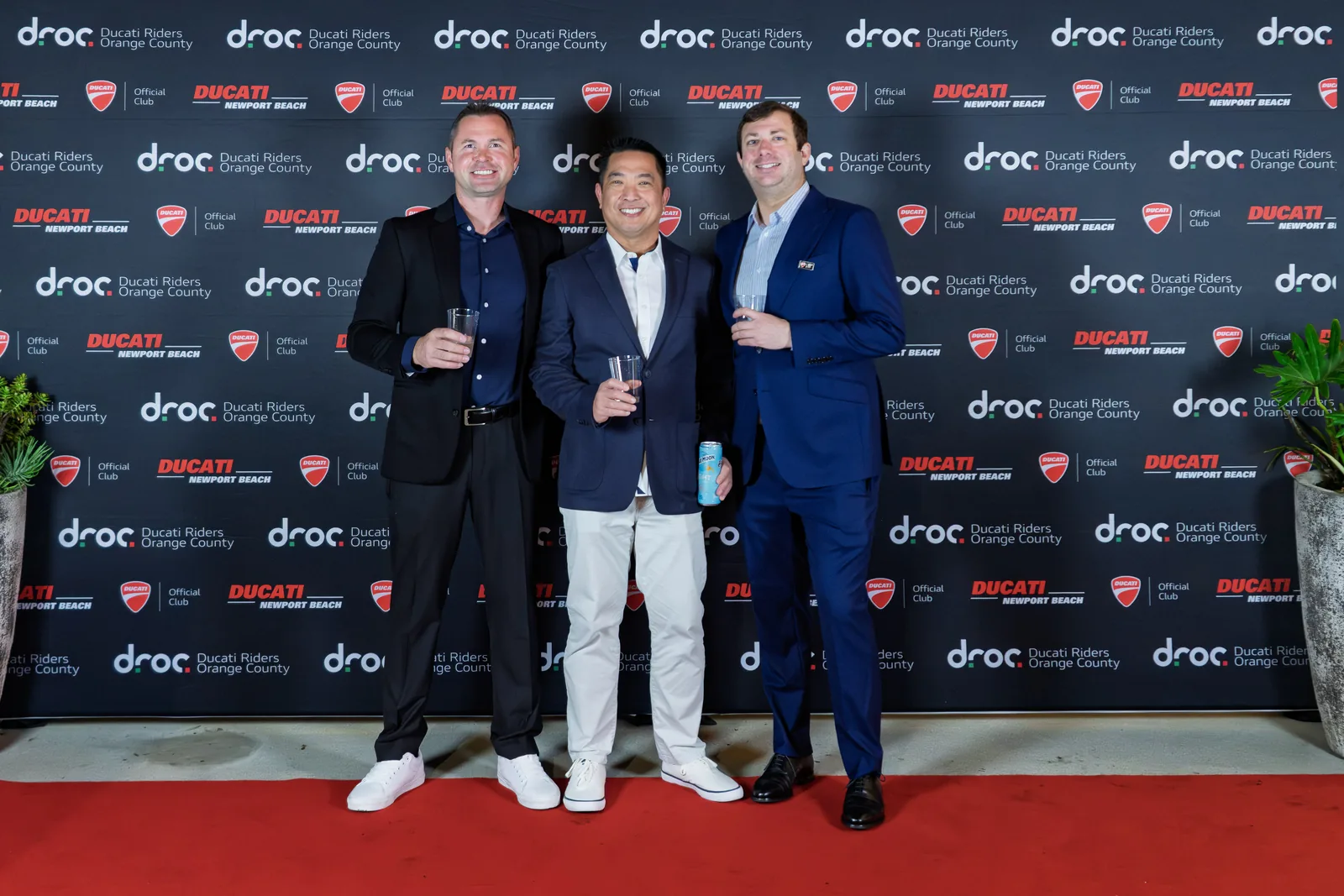 Jun Valenton: "Be very, very cautious, because it's very, very addicting" 7 Jun Valenton with two other members on the red carpet in front of the DROC and Ducati Newport Beach backdrop at the club holiday party