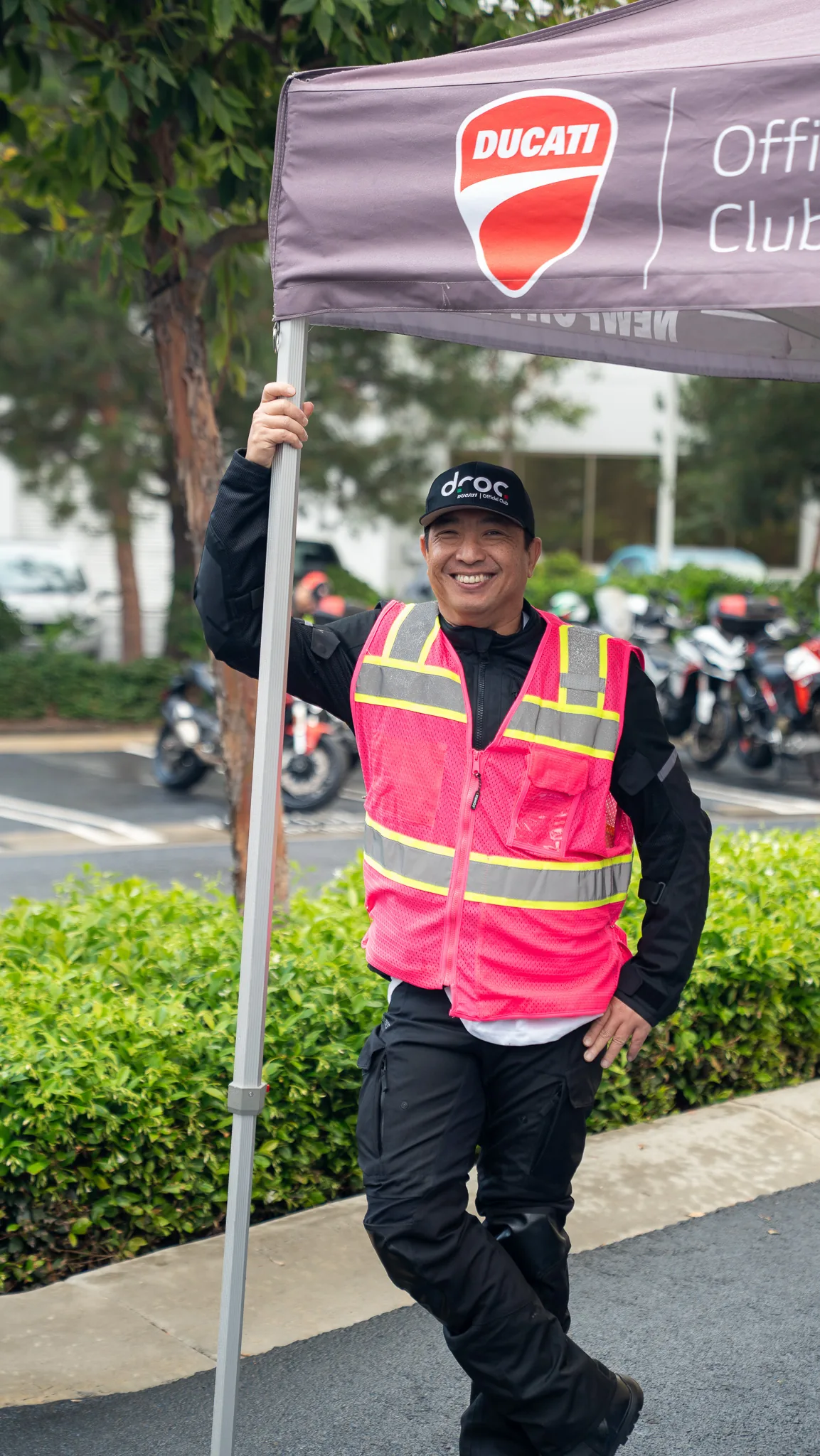 Jun Valenton: "Be very, very cautious, because it's very, very addicting" 5 Jun Valenton in a pink hi-viz ride leader vest and DROC cap under the Ducati Official Club tent at the We Ride As One start