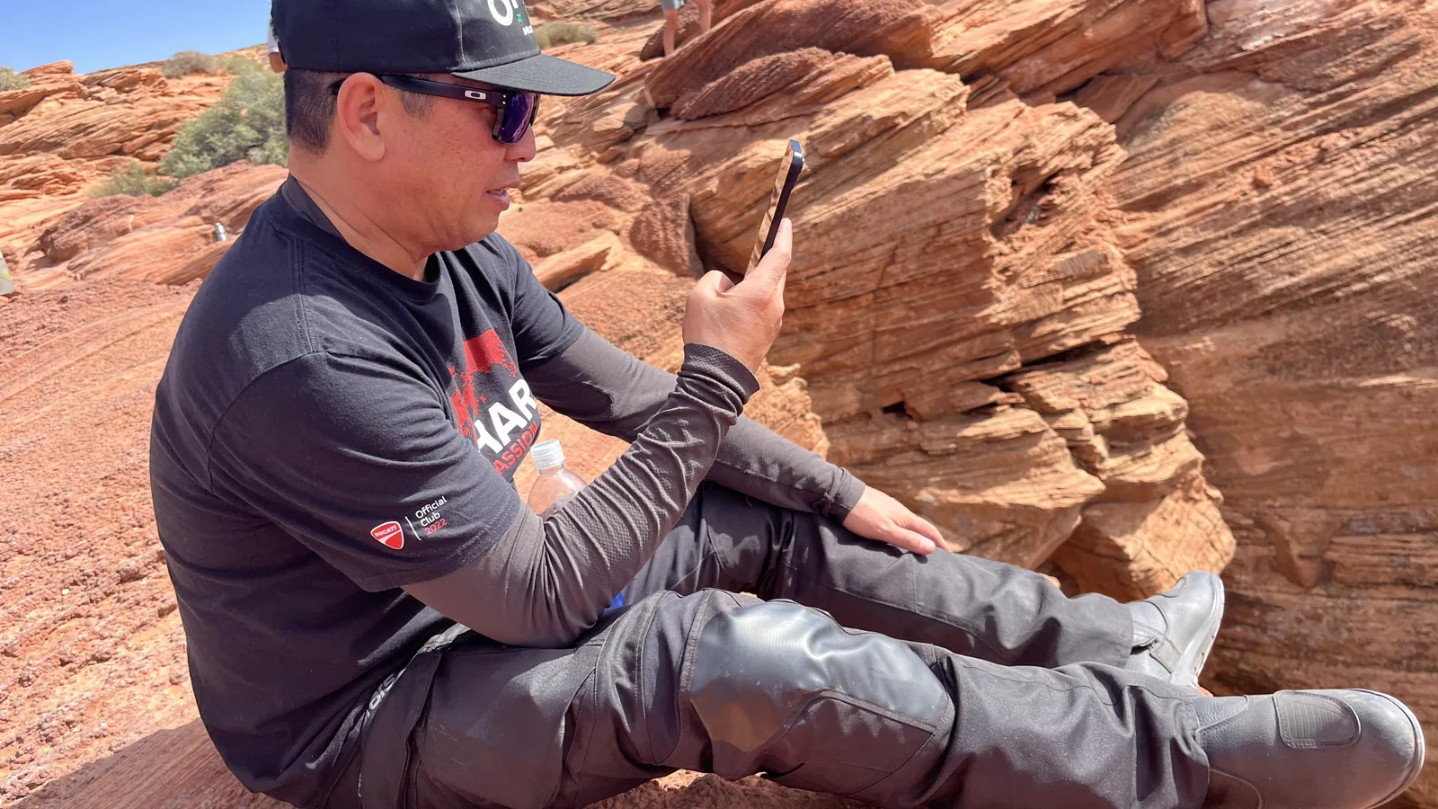 Jun Valenton: "Be very, very cautious, because it's very, very addicting" 6 Jun Valenton in adventure riding gear taking a break on red desert rock during a DROC ADV tour