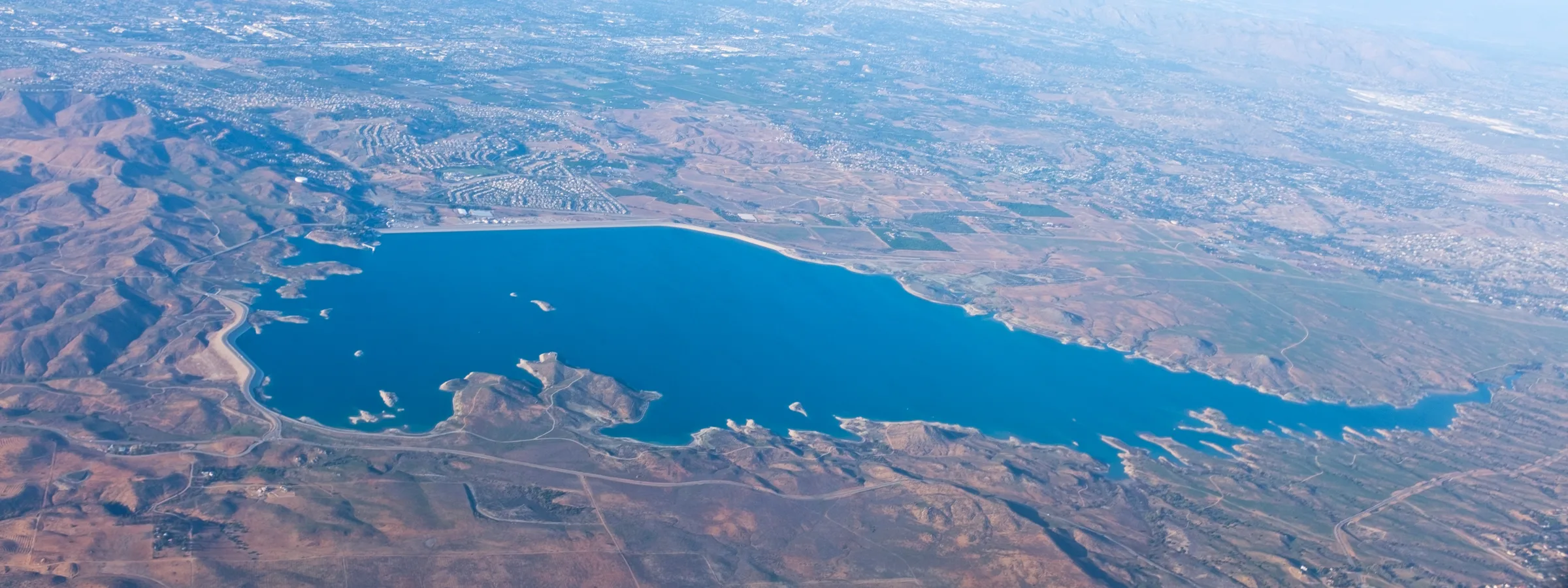 Lake Mathews rides 1 Aerial view of Lake Mathews, a deep blue reservoir ringed by brown hills, with Riverside County spreading out behind it