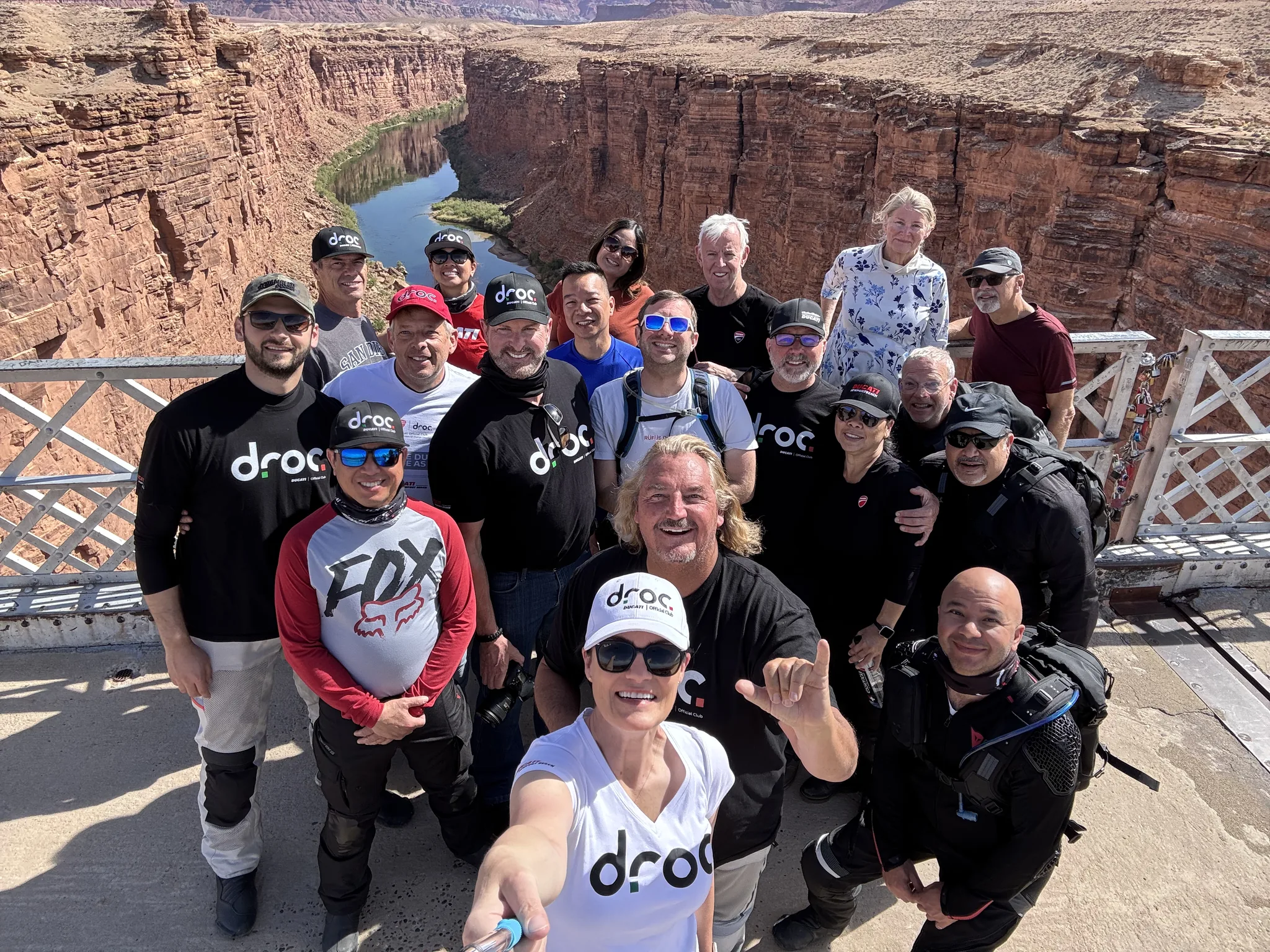 A group in black DROC t-shirts leans in for a selfie on the Navajo Bridge walkway above the Colorado River in Marble Canyon.