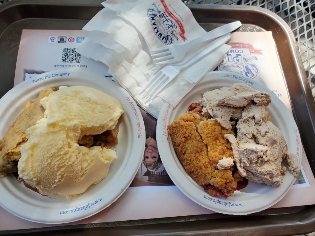 Two plates with slices of pie topped with vanilla and chocolate ice cream on a metal tray at Julian Pie Company