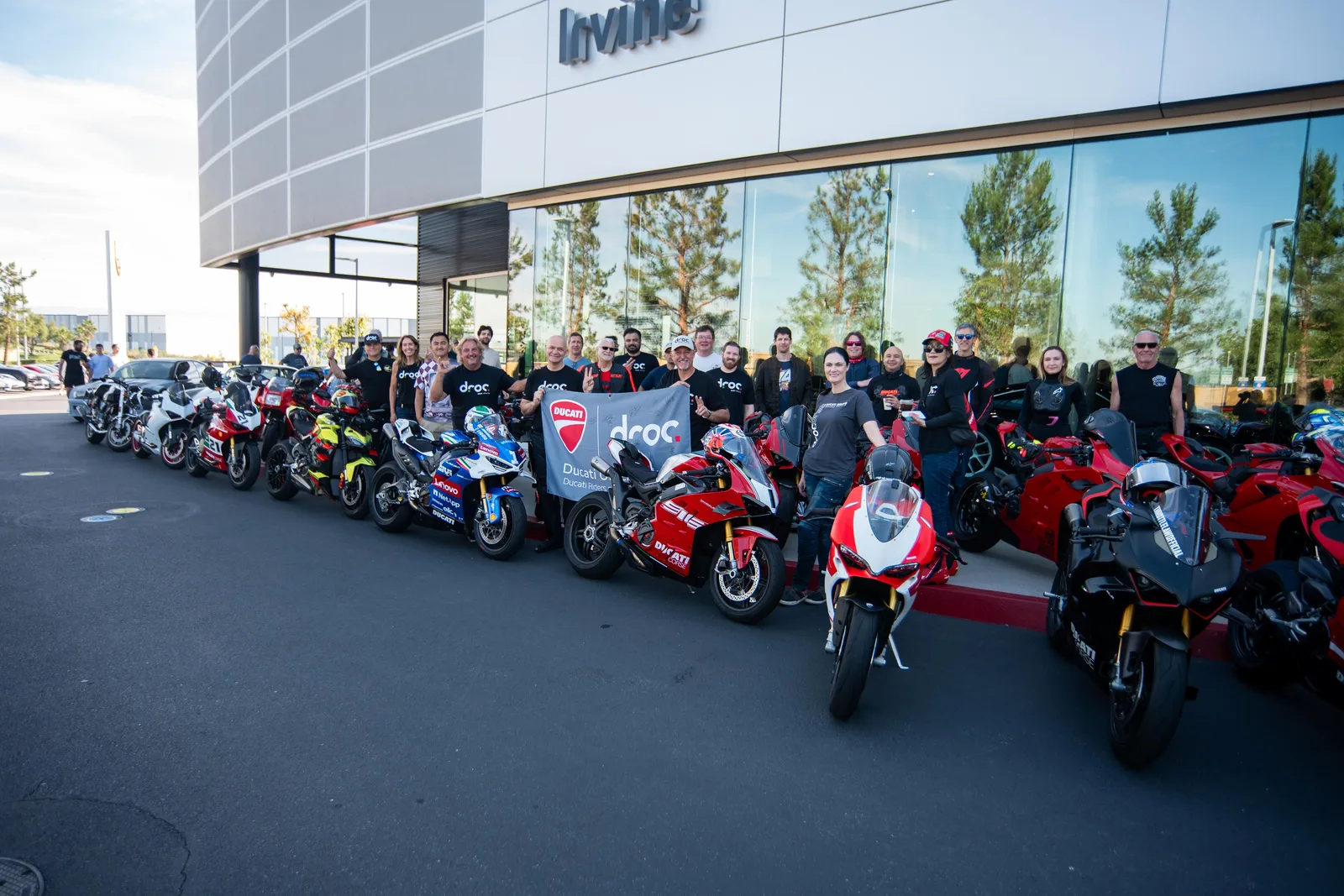 DROC members hold the club banner beside a row of Panigales outside Porsche Irvine at Cars and Coffee, March 21, 2026