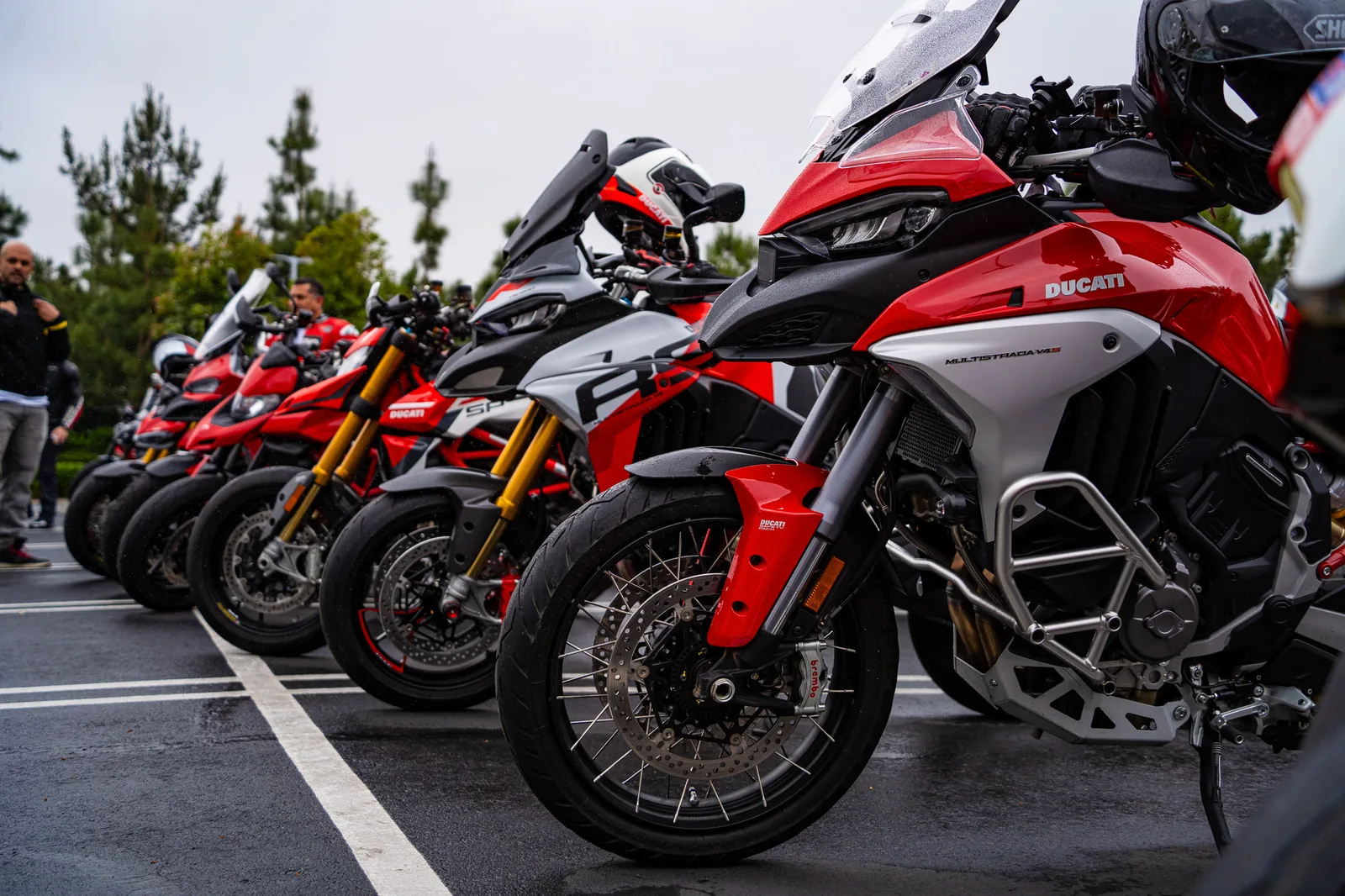A Multistrada V4 S leads a row of Multistradas and Hypermotards on wet pavement at Porsche Irvine, May 2025