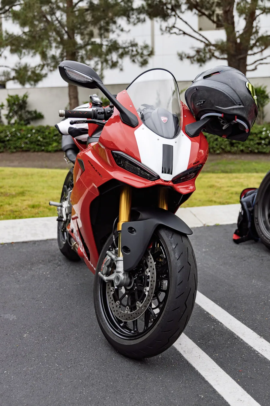 A red and white Panigale V2 with a helmet on the mirror, parked at Porsche Irvine before We Ride As One 2026
