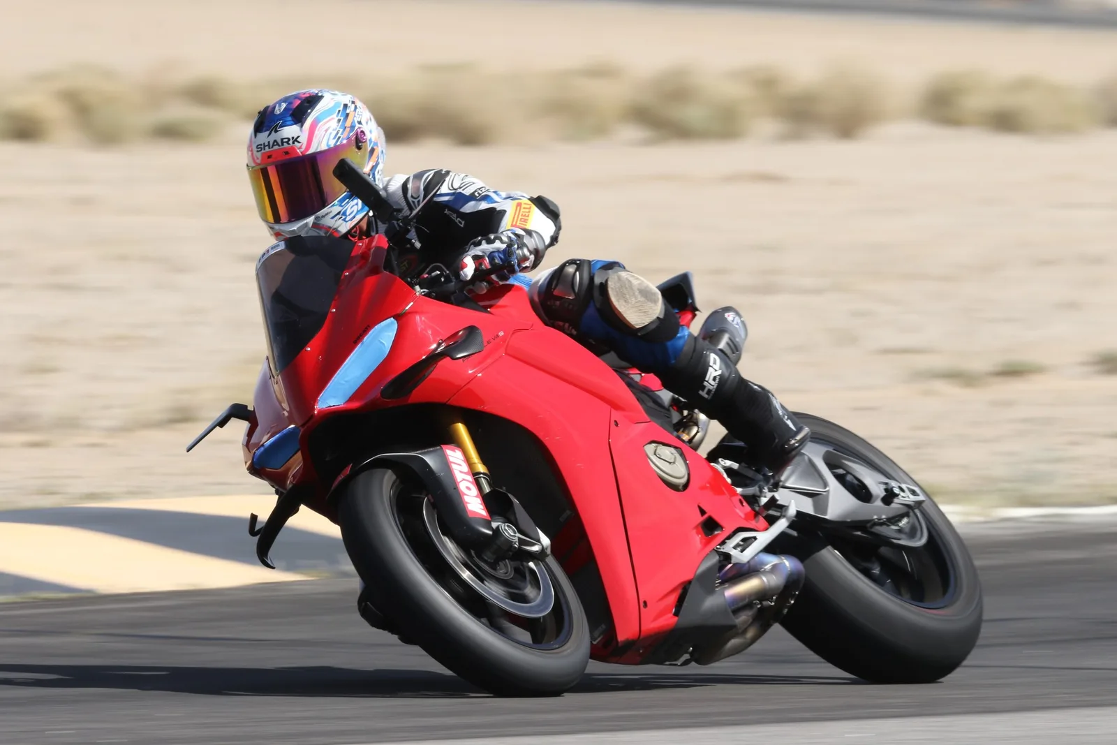 A rider in a Shark helmet leans a red Ducati Panigale hard into a corner past the curbing at Chuckwalla Valley Raceway, March 2026