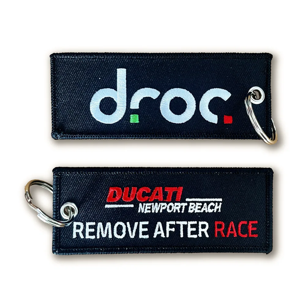 Both sides of the embroidered DROC keychain: the droc logo on the front, Ducati Newport Beach Remove After Race on the back
