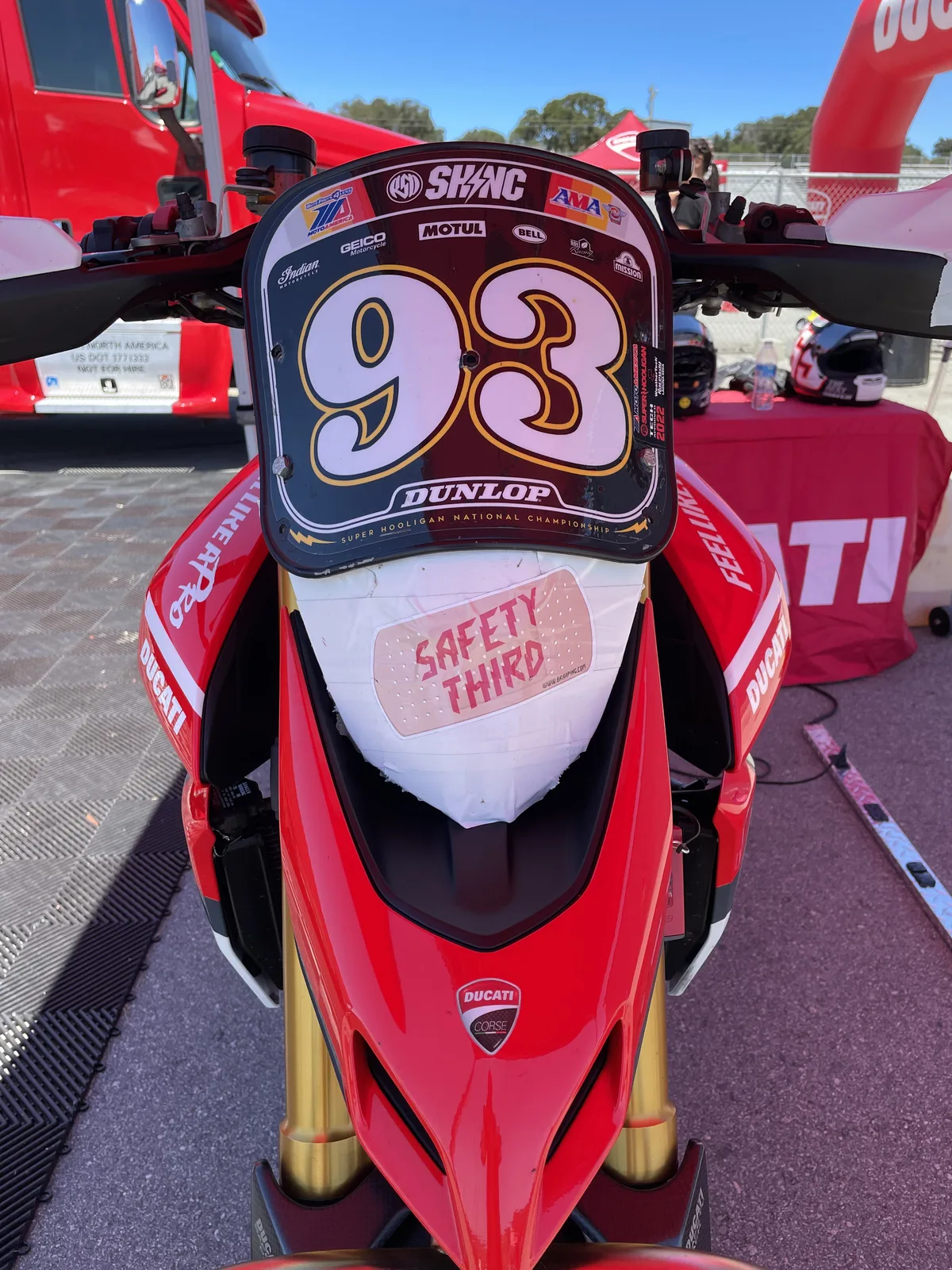 Front of a number 93 Super Hooligan Ducati Hypermotard race bike with a Safety Third sticker, parked in the Laguna Seca paddock, July 2022