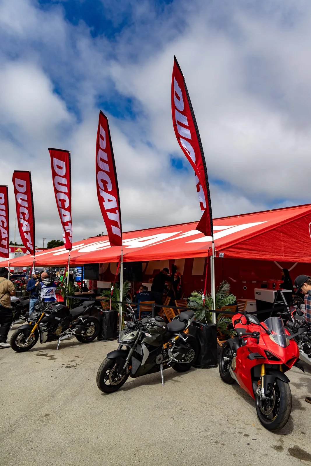 Red Ducati flags above a Ducati tent with Streetfighter V4 and Panigale V4 motorcycles parked in the Laguna Seca paddock, MotoAmerica weekend, July 2023