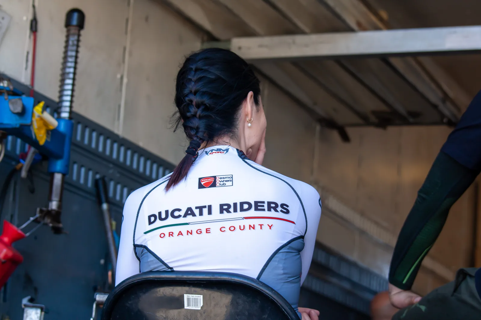 DROC track days at Streets of Willow 7 A rider seen from behind in a white Ducati Riders Orange County jersey sits in the open back of a paddock trailer at Streets of Willow, April 2022