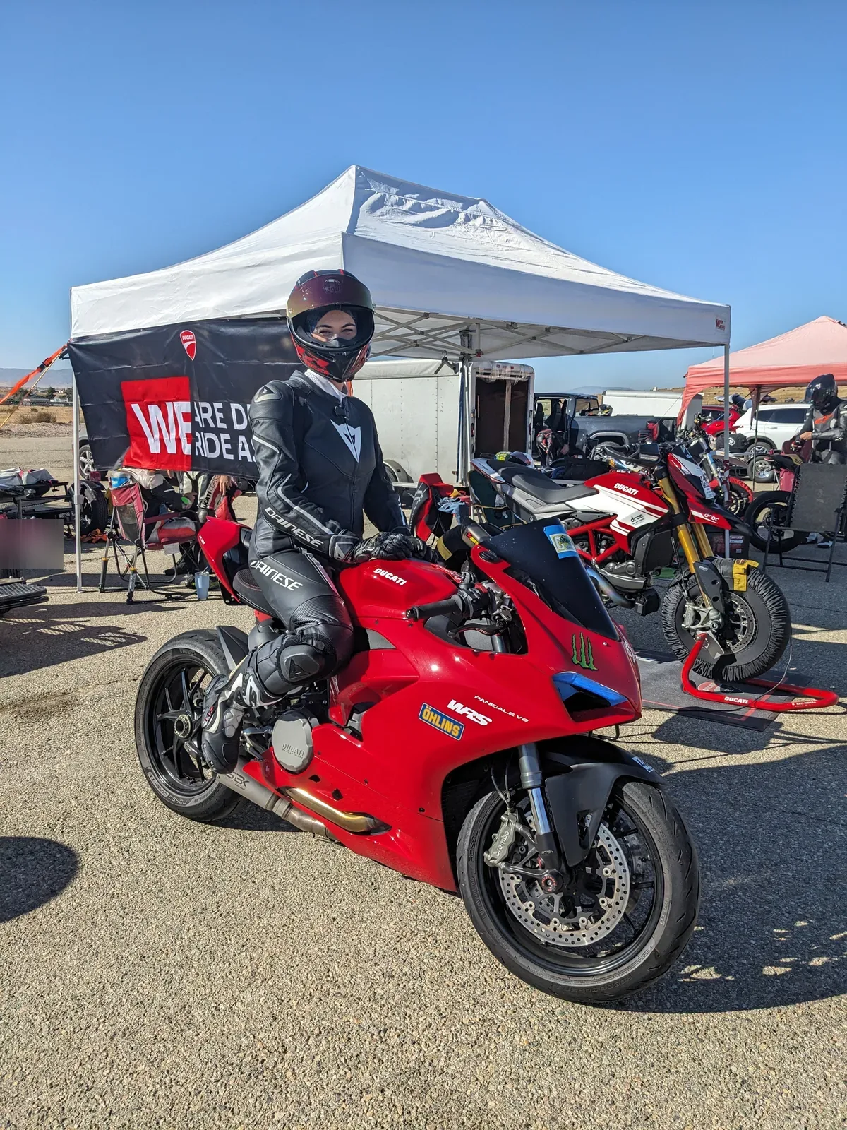 DROC track days at Streets of Willow 11 A rider in black leathers sits on a red Ducati Panigale V2 in front of a white canopy and a We Are Ducati banner in the paddock at Streets of Willow, November 2024