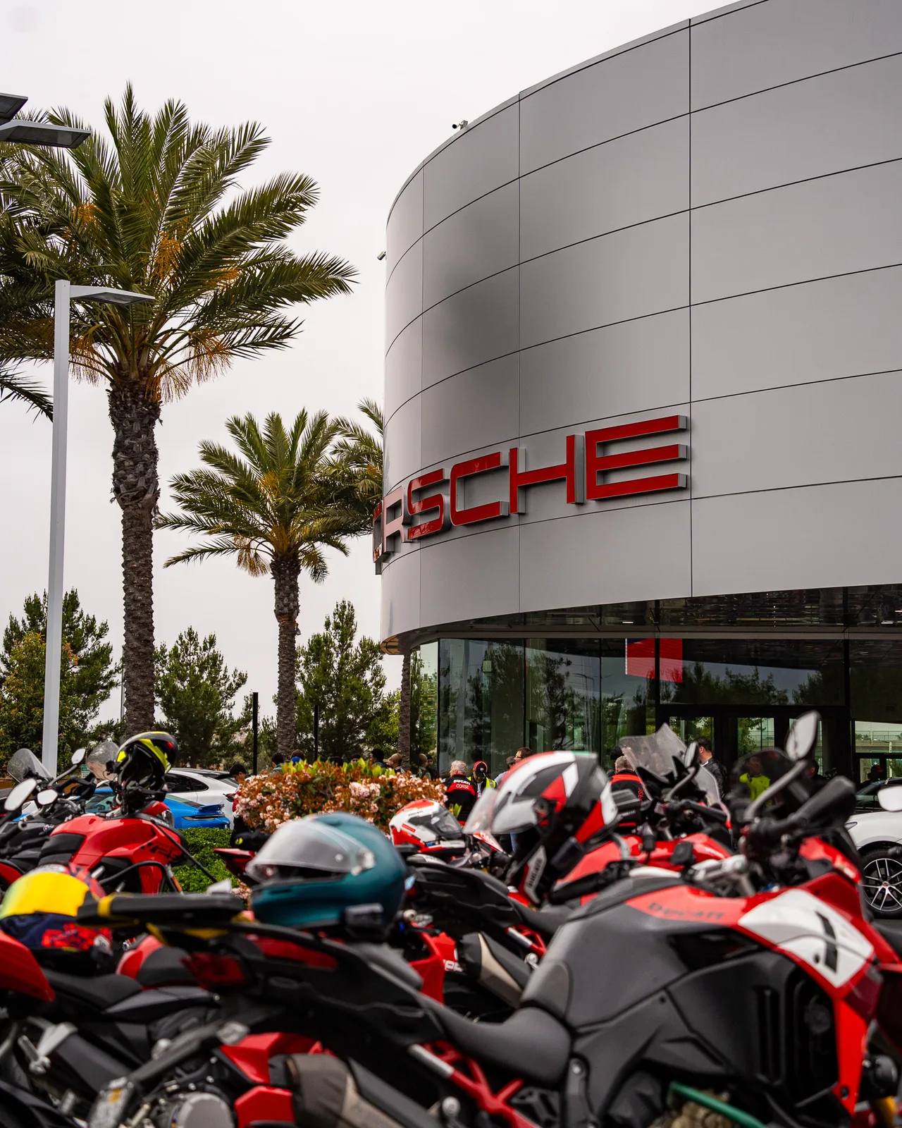 Ducati motorcycles and riders gather under the palms at Porsche Irvine before We Ride As One, May 3, 2025